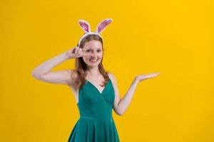 jeune femme avec des oreilles de lapin pour les vacances de pâques présentant une idée en souriant photo