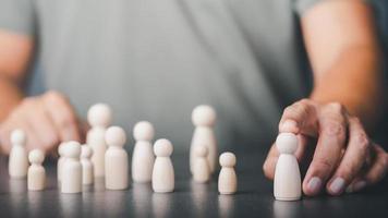 jeune homme pointant vers une poupée en bois, concept de gestion des ressources humaines, sélection du chef d'équipe, réussite et réalisation de la croissance, leadership et excellence. photo