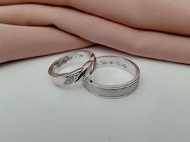 alliance en or blanc. bague couple avec finition brillante et doff avec fond en tissu marron et base blanche photo