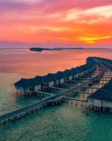 coucher de soleil paradisiaque des maldives. paysage aérien tropical, paysage marin avec long pont, villas sur l'eau avec une mer et une plage de lagon incroyables, nature tropicale. bannière de destination touristique exotique, vacances d'été photo