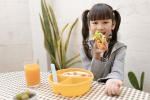 belle jeune fille mangeant le petit déjeuner et le jus d'orange sur la table de la maison de vacances. alimentation saine, aliments et collations, sandwich au jambon et au fromage, manger et être heureux photo