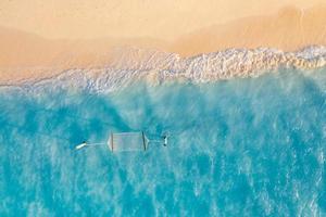 scène de plage aérienne relaxante, bannière de modèle de vacances de vacances d'été. les vagues surfent avec un incroyable lagon bleu océan, bord de mer, littoral. vue de dessus de drone aérien parfait. plage lumineuse paisible, bord de mer photo