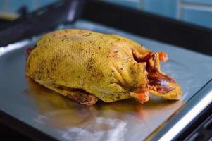 un canard plumé se trouve sur un plateau en fer dans la cuisine, cuit pour la cuisson dans du papier d'aluminium, la cuisson. photo