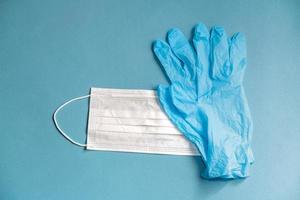 masque blanc chirurgical et gants en latex pour la protection sur fond bleu photo