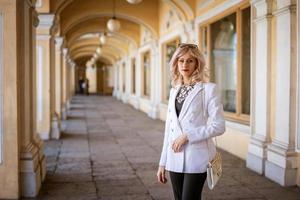 une femme d'affaires dans une veste blanche se tient dans la rue photo