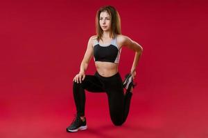 jeune femme athlète est engagée dans le fitness en studio sur fond rouge photo