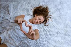 heureuse jeune femme se réveiller dans un lit blanc confortable photo