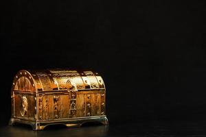 un coffre en or avec des bijoux sur fond noir. photo