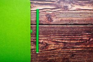 bloc-notes vert avec un stylo-feutre sur une table en bois marron, vue de dessus. photo