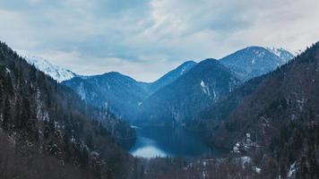 lac d'hiver ritsa en abkhazie avec des montagnes dans la neige en arrière-plan, tard dans la soirée. photo