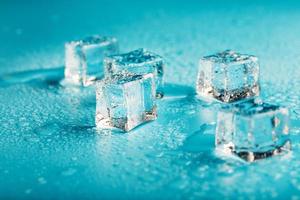 les glaçons sont parsemés de gouttes d'eau éparpillées sur un fond bleu. photo