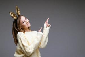 belle jeune femme aux oreilles de lapin montre son doigt à l'arrière-plan photo