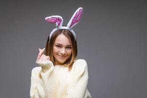 jeune fille souriante avec des oreilles de lapin montre un mini coeur avec les doigts photo