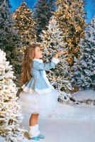 jolie fille blonde caucasienne marchant dans la forêt de Noël d'hiver avec des lumières. nouvel an, concept de conte de fées photo