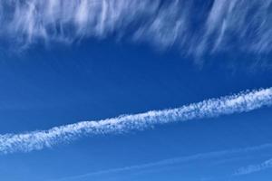 Contraintes de condensation des avions dans le ciel bleu entre quelques nuages photo