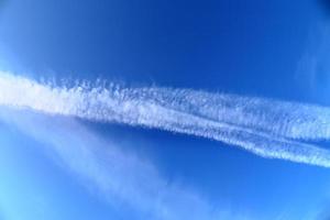 Contraintes de condensation des avions dans le ciel bleu entre quelques nuages photo