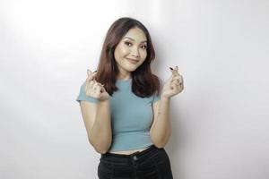 une jolie jeune femme asiatique portant un t-shirt bleu se sent heureuse et un geste de coeur aux formes romantiques exprime des sentiments tendres photo