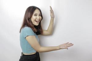 femme asiatique excitée portant un t-shirt bleu pointant vers l'espace de copie à côté d'elle, isolée par fond blanc photo