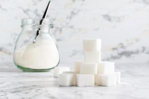 cubes de sucre et sucre granulé dans un bocal sur la table. photo