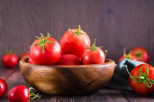 tomates mûres biologiques dans un bol sur une table en bois. récolte et produits locaux.