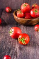 tomates biologiques mûres sur une table en bois. récolte et produits locaux. vue verticale photo