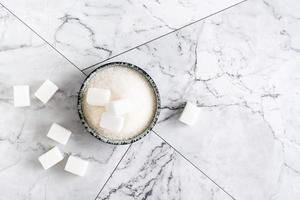 sucre granulé et morceaux de sucre dans un bol sur la table. vue de dessus. photo