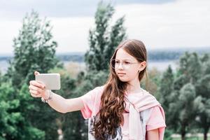 une fille sérieuse à lunettes prend un selfie vidéo sur un smartphone. contenu pour les réseaux sociaux photo