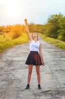 jeune fille debout sur la route avec sa main levée, le concept de succès. photo