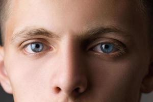 portrait d'un mec en gros plan regardant la caméra aux yeux bleus photo