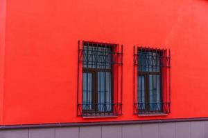 façade rouge du bâtiment avec des fenêtres en bois sur lesquelles se trouvent des barres de fer