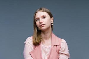 femme modeste et naïve aux cheveux blonds, élégamment vêtue d'un gilet rose photo