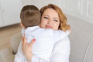 une femme heureuse s'amuse avec un mignon petit garçon de 5-6-7 ans en chemise blanche. maman photo
