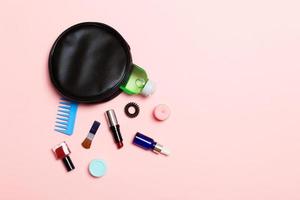 vue aérienne d'un sac de cosmétiques en cuir avec des produits de beauté maquillage débordant sur fond rose. beau concept de peau avec espace de copie photo