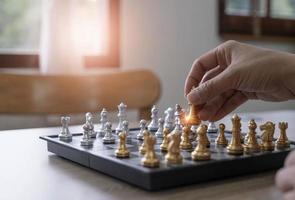 gros plan main d'homme déplaçant la figure d'échecs dans le jeu de succès de la compétition. concept de stratégie, de gestion ou de leadership photo