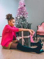 femme afro-américaine malheureuse et joyeuse avec boîte présente sur le fond de l'arbre de noël. noël, nouvel an, bonheur, concept de vacances photo