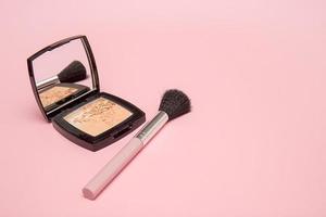 poudre et pinceau de maquillage sur fond rose photo