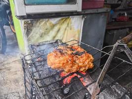 poitrine de poulet enveloppée de farine croustillante avec un délicieux assaisonnement épicé sur le gril chaud. poulet grillé typique d'indonésie photo