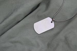 Perles militaires argentées avec dog tag sur uniforme de fatigue vert foncé photo