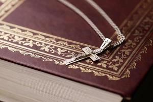 collier en argent avec croix crucifix sur le livre chrétien de la sainte bible sur une table en bois noire. demander des bénédictions à Dieu avec le pouvoir de la sainteté, ce qui porte chance photo