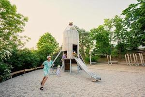 enfants dans une aire de jeux pour enfants toboggan de fusée dans un parc public. photo