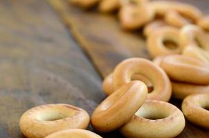 beaucoup de bagels jaunes frais se trouvent à la surface du vieux bois sombre. un type populaire de produits à base de farine. l'une des friandises russes traditionnelles pour le thé photo