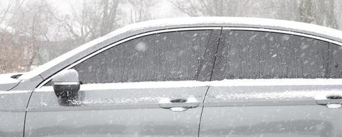 fragment de la voiture sous une couche de neige après une forte chute de neige. le corps de la voiture est recouvert de neige blanche photo