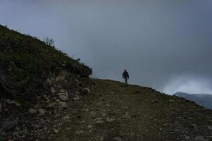 un homme de dos avec un sac à dos fait du trekking dans les montagnes dans le brouillard photo