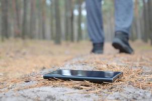 jeune homme perd son smartphone sur le chemin du bois de sapin d'automne russe. négligence et perte d'un concept d'appareil mobile coûteux photo