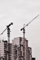 travailler de grandes grues à l'intérieur de la place pour de grands immeubles en construction contre un ciel bleu clair. progression des travaux de la grue et du bâtiment. ton rétro photo