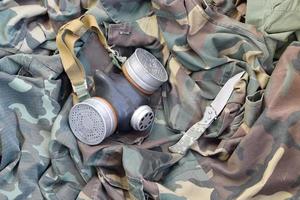 Le masque à gaz soviétique des soldats harceleurs se trouve avec un couteau sur des vestes de camouflage vert kaki photo