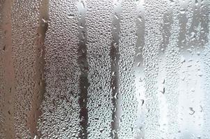 la texture d'un verre embué avec beaucoup de gouttes et de flux de condensation. image de fond photo