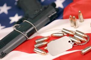 de nombreuses balles et armes à feu jaunes de 9 mm avec des plaques d'identification sur le drapeau des états-unis. concept de devoir et de service dans les forces armées américaines photo