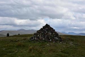 grand repère de cairn au sommet d'une grande colline photo