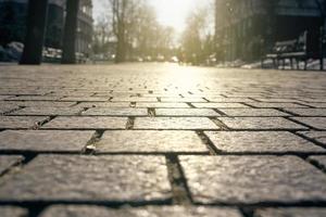 carreaux de pavage éclairés par le fond de la lumière du soleil. dalles de pavage en gros plan sur le fond des rues, des arbres et du ciel en flou. photo